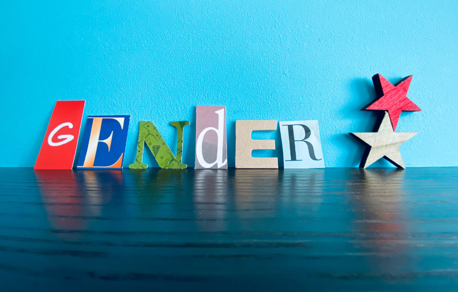 Das Wort GENDER steht in Holzbuchstaben mit Sternchen vor einer blauen Wand