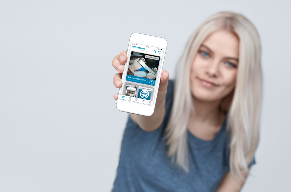 Blonde junge Frau hält Mobiltelefon in in die Kamera