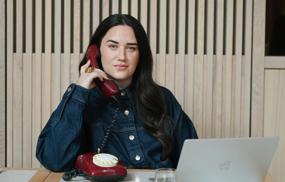 Selma Sadikovic am Schreibtisch mit Laptop und rotem Telefon